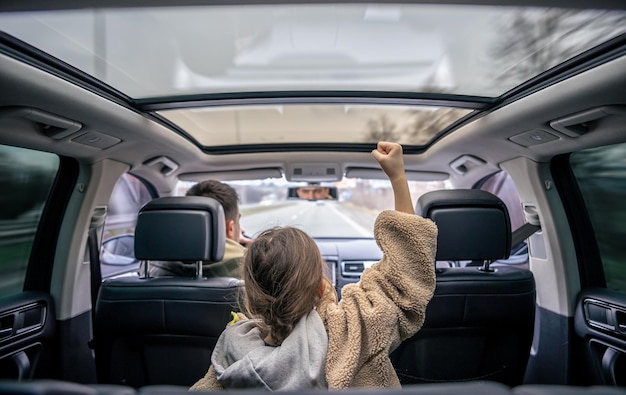 Little girl listens enjoys music and dancing in the car while family road trip