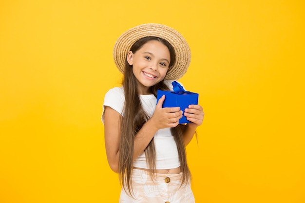 小さな女の子の長い髪の夏の帽子はギフトボックスの誕生日プレゼントのコンセプトを保持します