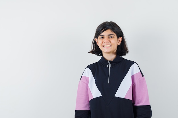 Little girl looking at camera in shirt and looking merry , front view.