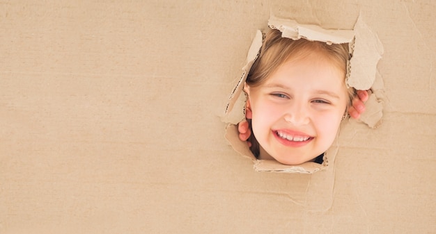 Little girl looking straigt from cardboard box