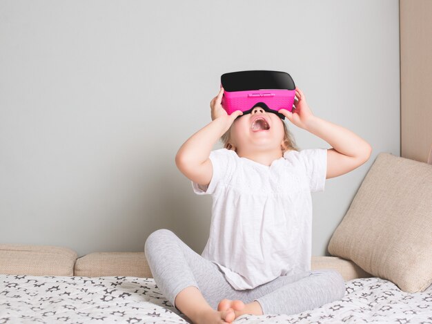 Little girl looking in virtual reality glasses at home. Scandinavian interior