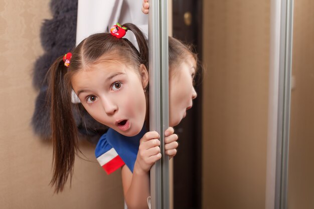 Little girl looks out of the closet.