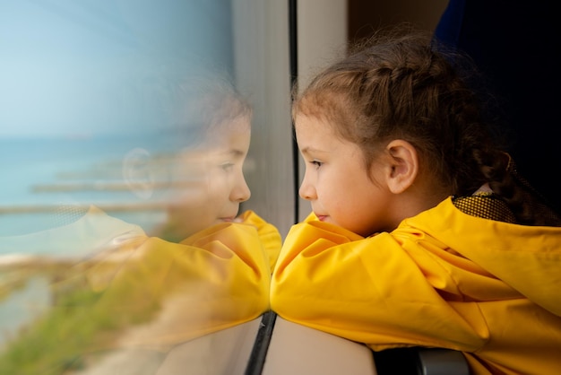 어린 소녀는 바다에서 기차의 창 밖을 내다 여름 가족 휴가