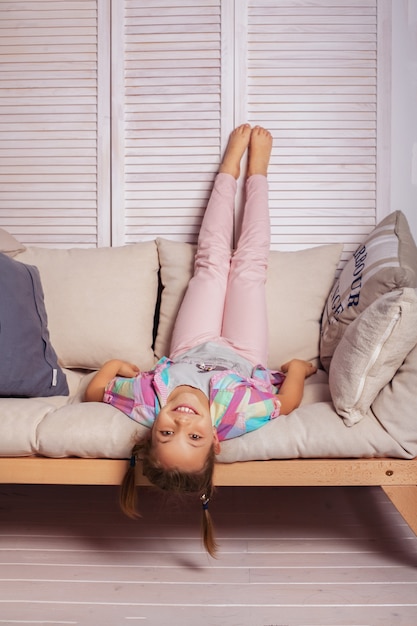 Little girl lying on couch upside down. childhood