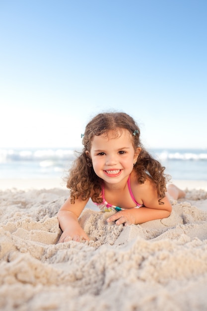 Little girl lying down on the beach