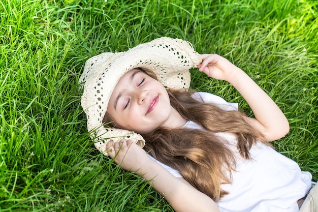 잔디에 누워있는 어린 소녀. 여름 시간과 화창한 날