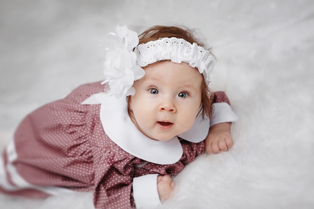 Little girl lying and looking at the camera. Beautiful dress and head decoration