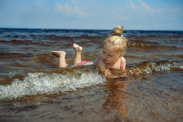 Little girl lying in sea in waves