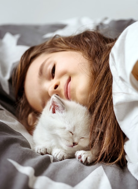 Little girl lying on sofa with white cat