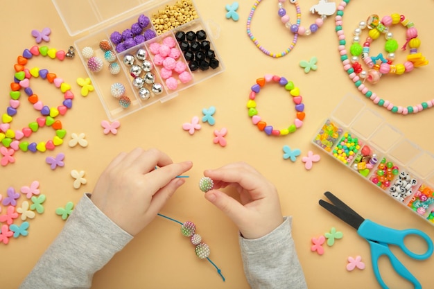 Photo little girl made bracelets on beige background kids handmade beaded jewelry diy bracelet beads