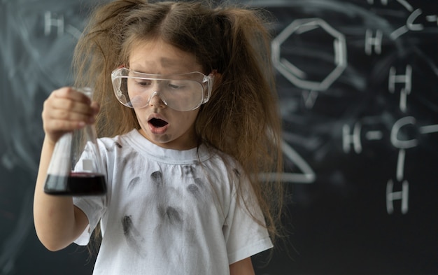 Little girl makes experiments in chemistry lesson explosion during mixing surprise on the face place...