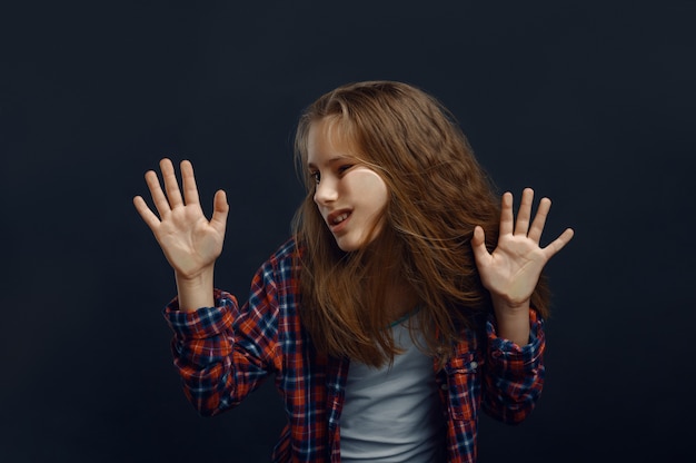 Photo little girl makes face leaning against the glass