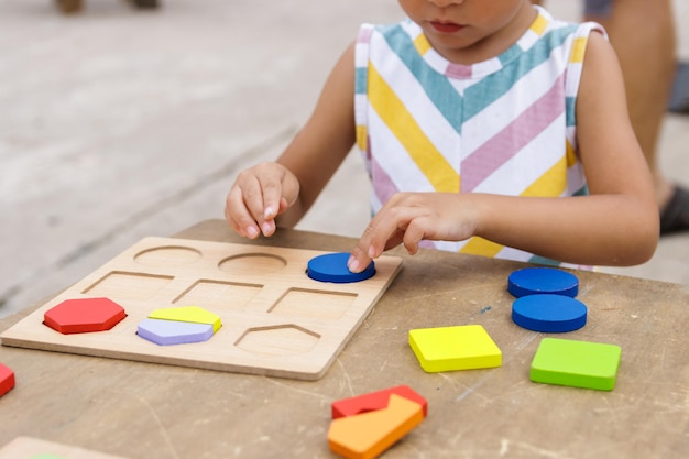 Little girl making colorful wooden puzzle