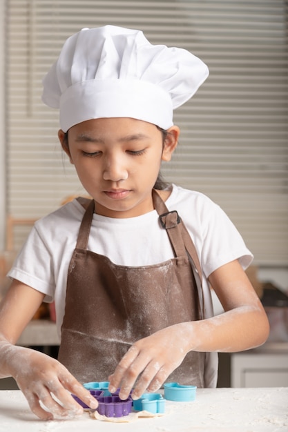 Foto la bambina che produce i biscotti nella cucina.