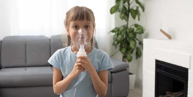 Фото Маленькая девочка делает ингаляцию небулайзером дома. детская астма ингалятор ингаляционный небулайзер паровой больной кашель концепция.