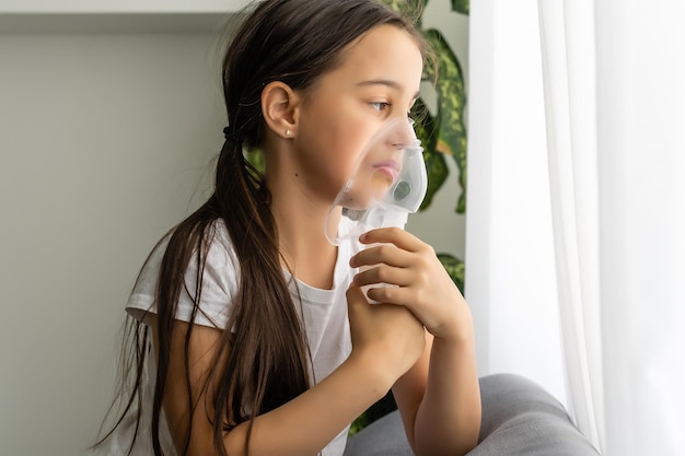 Little girl making inhalation with nebulizer at home. child asthma inhaler inhalation nebulizer steam sick cough concept.