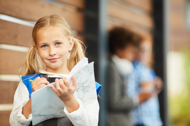 Little girl making notes in textbook