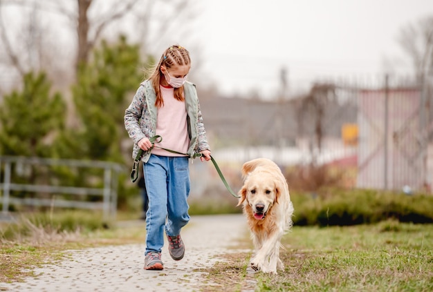 Little girl in mask with golden retriever dog