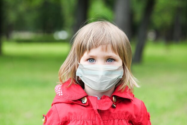 Little girl in medical protective face mask outdoor