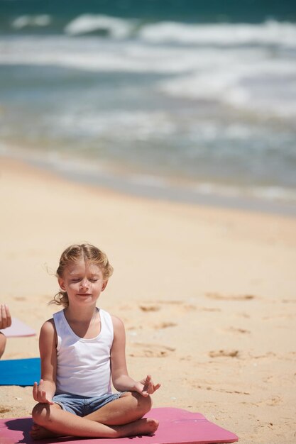 Bambina che medita sulla spiaggia