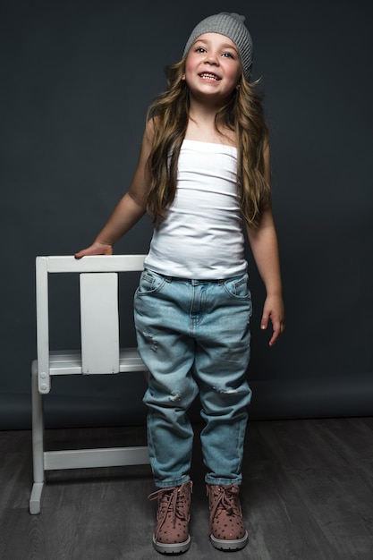 Little girl model professionally posing in the studio in jeans and a white Tshirt Model tests