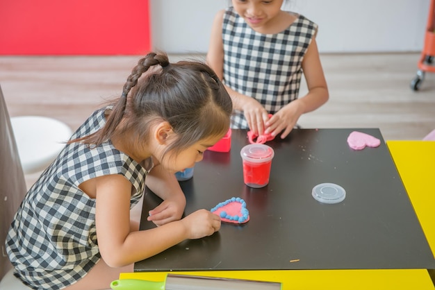 일부 제품을 위해 다채로운 점토를 성형하는 어린 소녀는 상상에서 생각하는 행복한 아이들의 놀이 개념