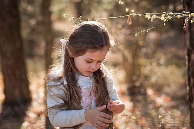 little girl on nature examines plants