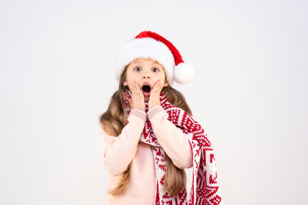 A little girl in a New Year's costume holds her palms near her cheeks and is very surprised.