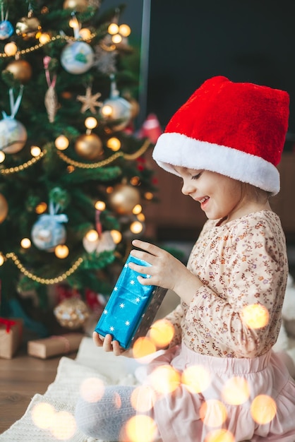 Little girl opening a gift box near the Christmas tree