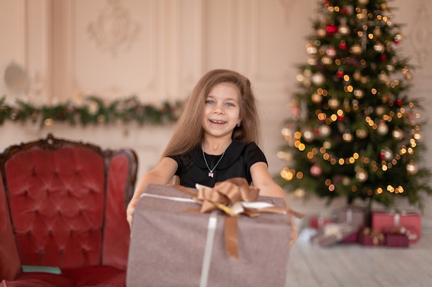 A little girl opens a Christmas present from Santa. Christmas tale. Happy childhood.