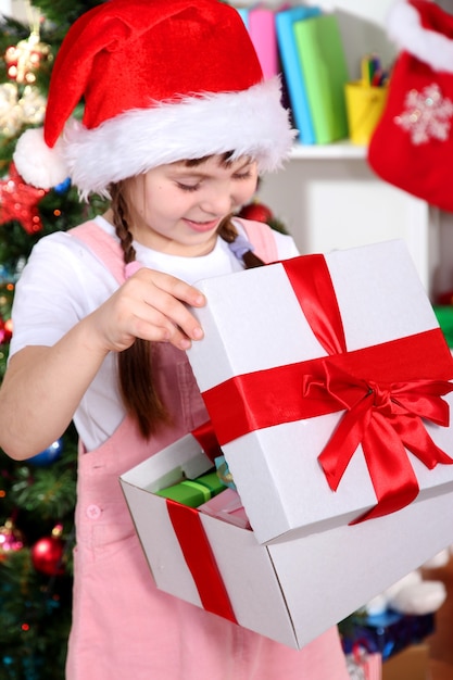 A little girl opens a gift in festively decorated room