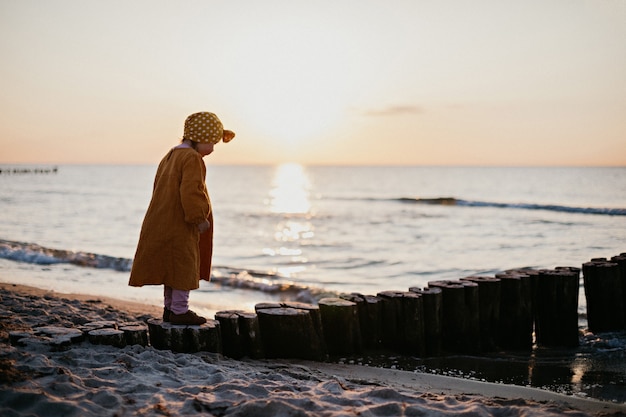 日没時にビーチに沿って歩く東洋の服を着た少女