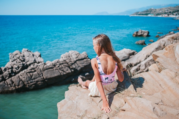 Little girl outdoor on edge of cliff seashore