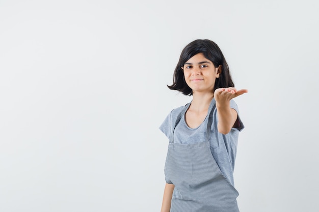 Little girl outstretching hand in t-shirt and looking gentle , front view.