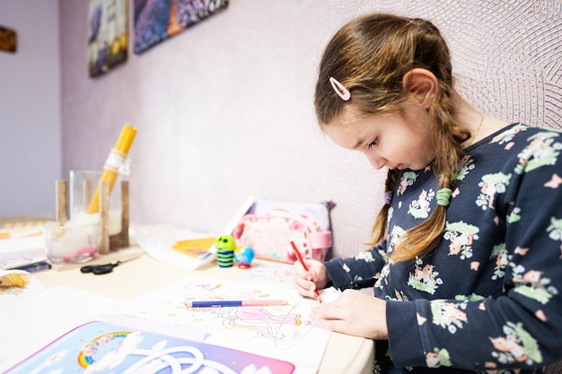 Little girl painting by pencil at home