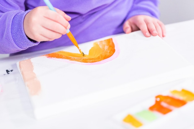 Photo little girl painting on canvas with arcylic paint.