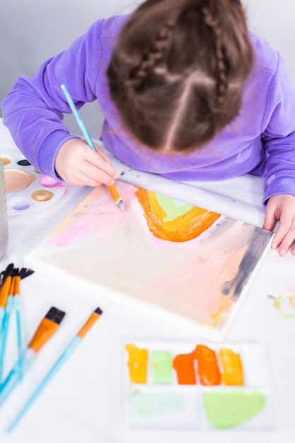 Little girl painting on canvas with arcylic paint.