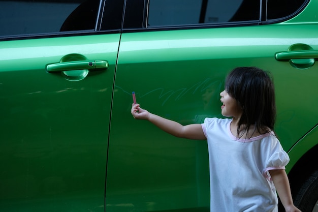 Photo little girl painting and drawing on her own father car