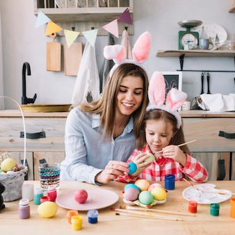 Bambina che dipinge le uova per pasqua con la madre