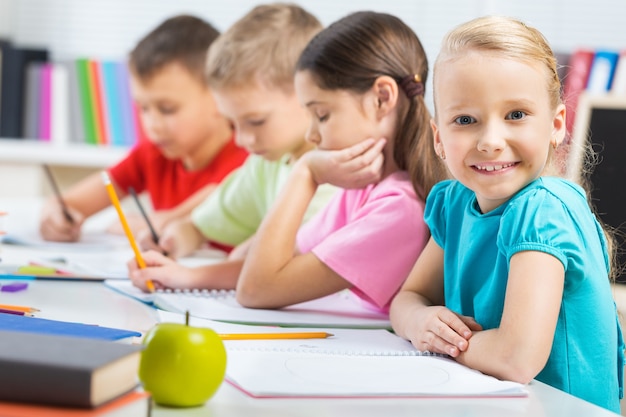 Little girl on painting lesson in school with blurred boys on background