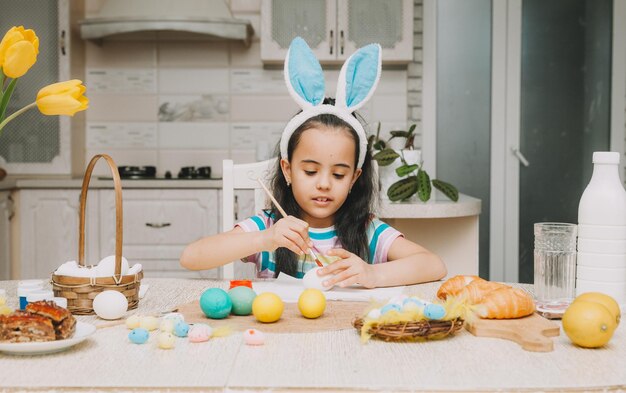 Little girl paints easter eggs Happy family is preparing for Easter Cute little girl with bunny ears on Easter day