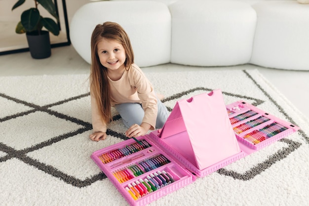 Маленькая девочка рисует дома милая девушка сидит на полу