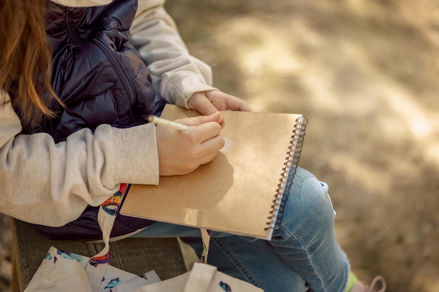 Little girl paints in open air in spring blooming fairytale park Children39s drawings Creative kid Joy of childhood