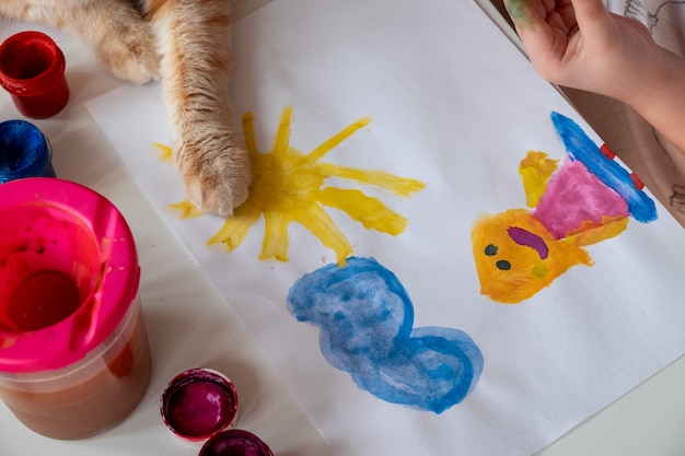 A little girl paints the sun and her mother with watercolors