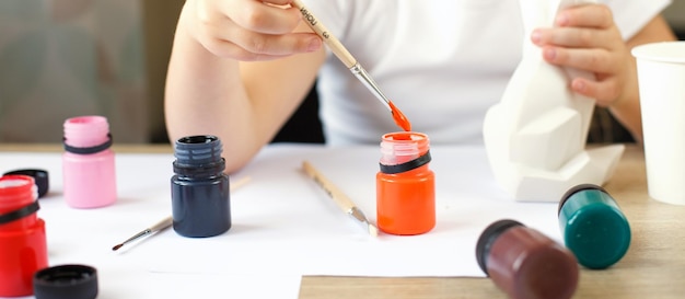 A little girl paints a toy fox made of clay DIY concept