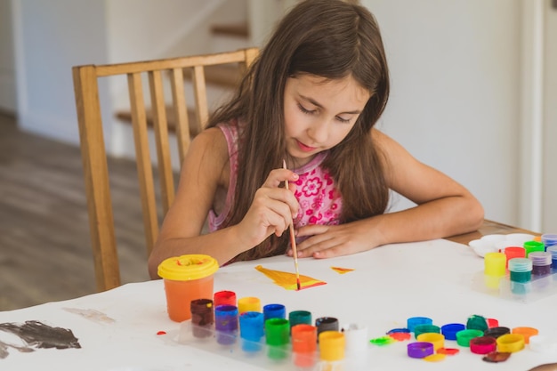 La bambina dipinge con i colori da sola a casa