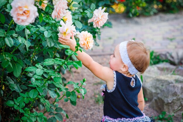 Little girl in the park stretches in roses