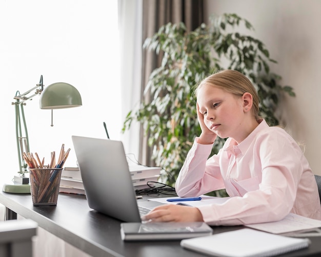 Foto bambina che partecipa a lezioni online al chiuso