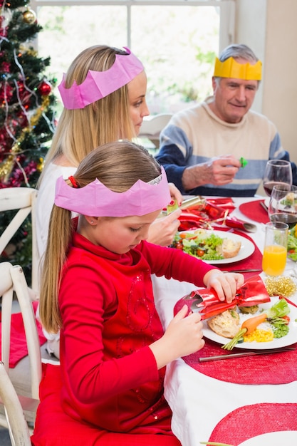 クリスマスのクラッカーを保持しているパーティーの帽子の少女