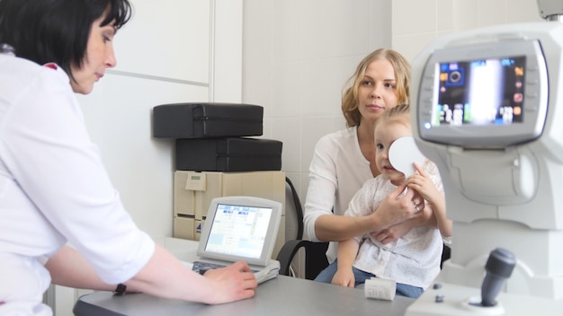 Little girl - patient in ophthalmologist room - child with mommy at the on consultation, close up